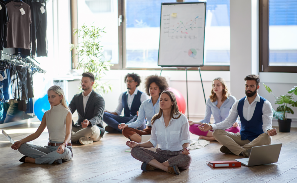 Mitarbeiter und Führungskräfte praktizieren gemeinsam Achtsamkeit und Meditation im Büro – Resilienztraining für Unternehmen