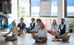 Mitarbeiter und Führungskräfte praktizieren gemeinsam Achtsamkeit und Meditation im Büro – Resilienztraining für Unternehmen