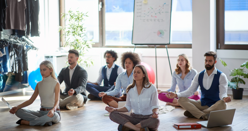 Mitarbeiter und Führungskräfte praktizieren gemeinsam Achtsamkeit und Meditation im Büro – Resilienztraining für Unternehmen